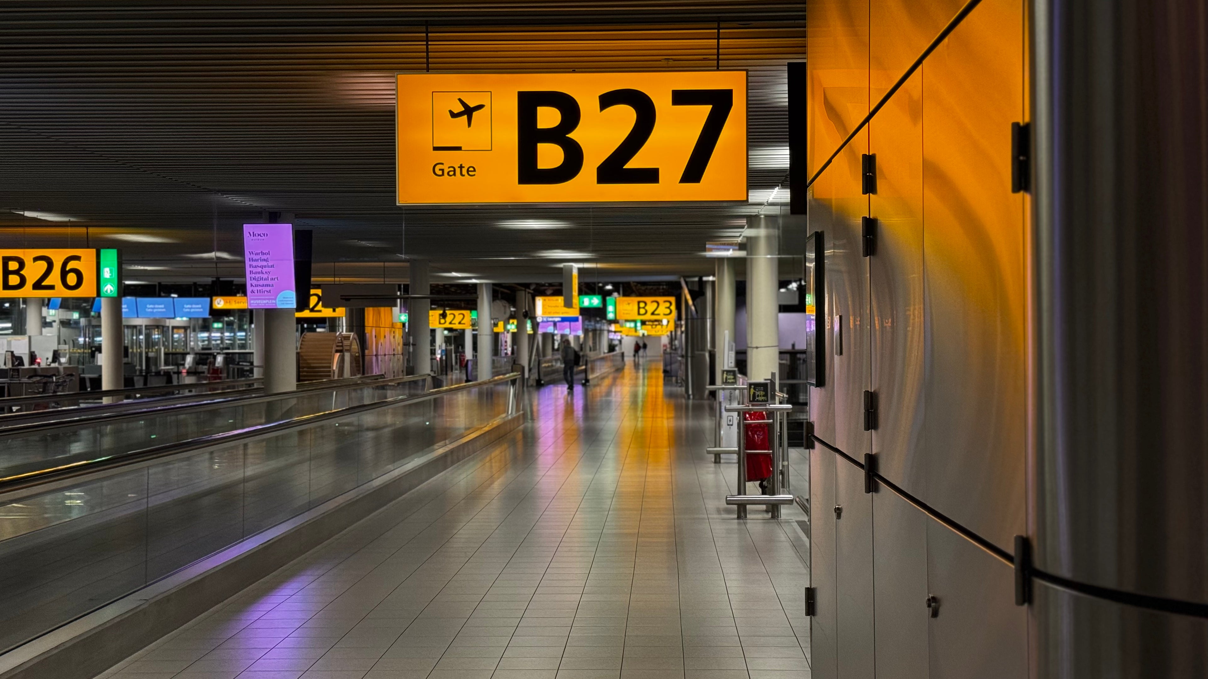 Airport terminal with 'B27' gate sign and walkway.